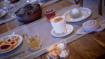Una mesa de comedor con platos de comida, vasos de bebida y un bol de postre.