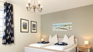 Un dormitorio con cama, mesita de noche, lámpara, candelabro y cuadros en la pared.