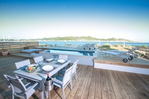 A deck with a pool, lounge chairs, and a table set for dining. - Cliff House (Simpson Bay)