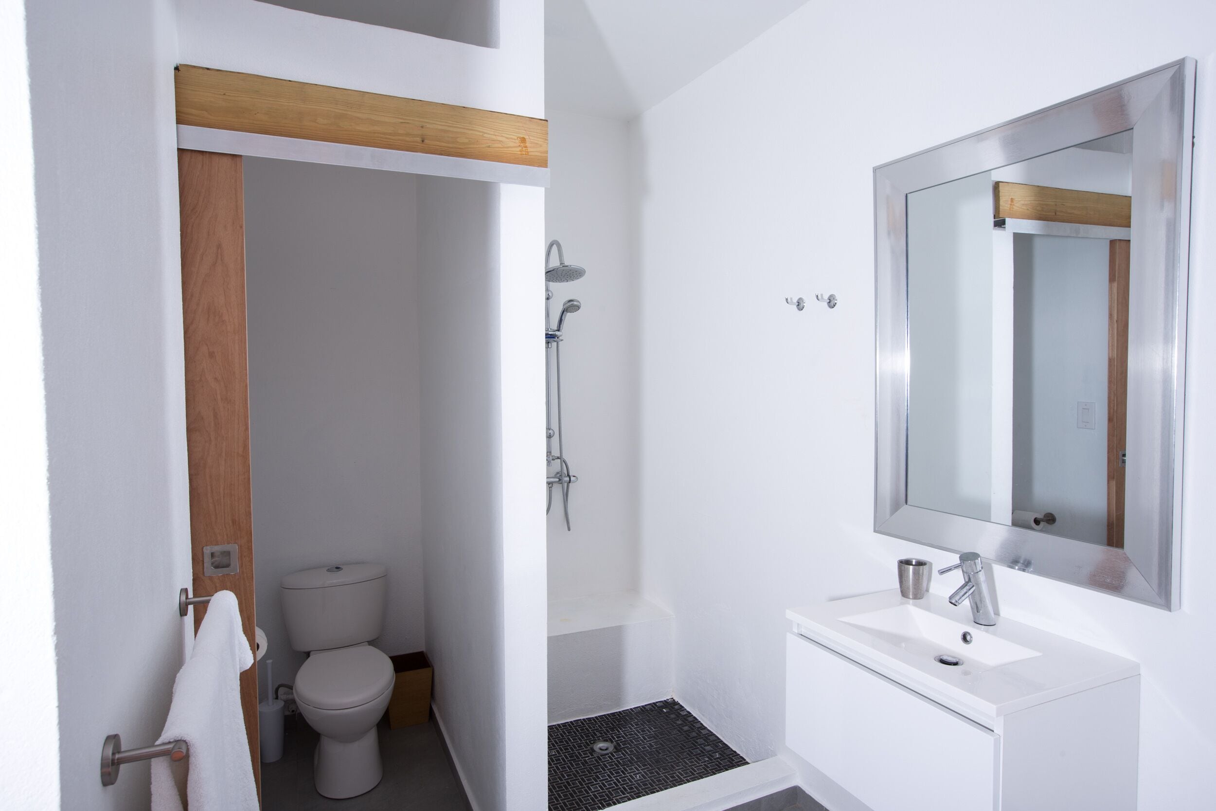 A modern bathroom with a toilet, shower, and sink.