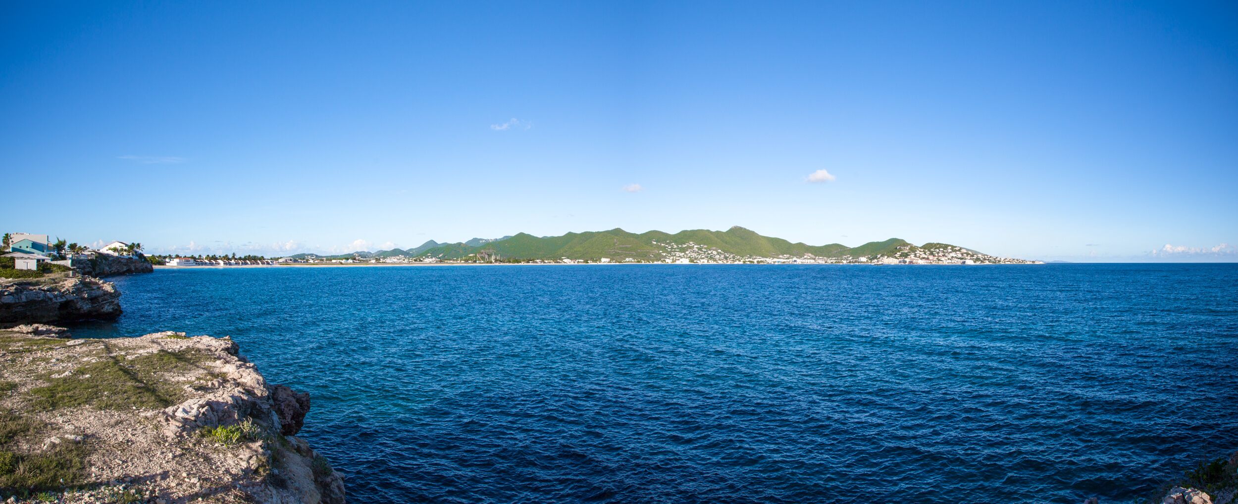 A coastal view with rocky terrain and a distant cityscape.