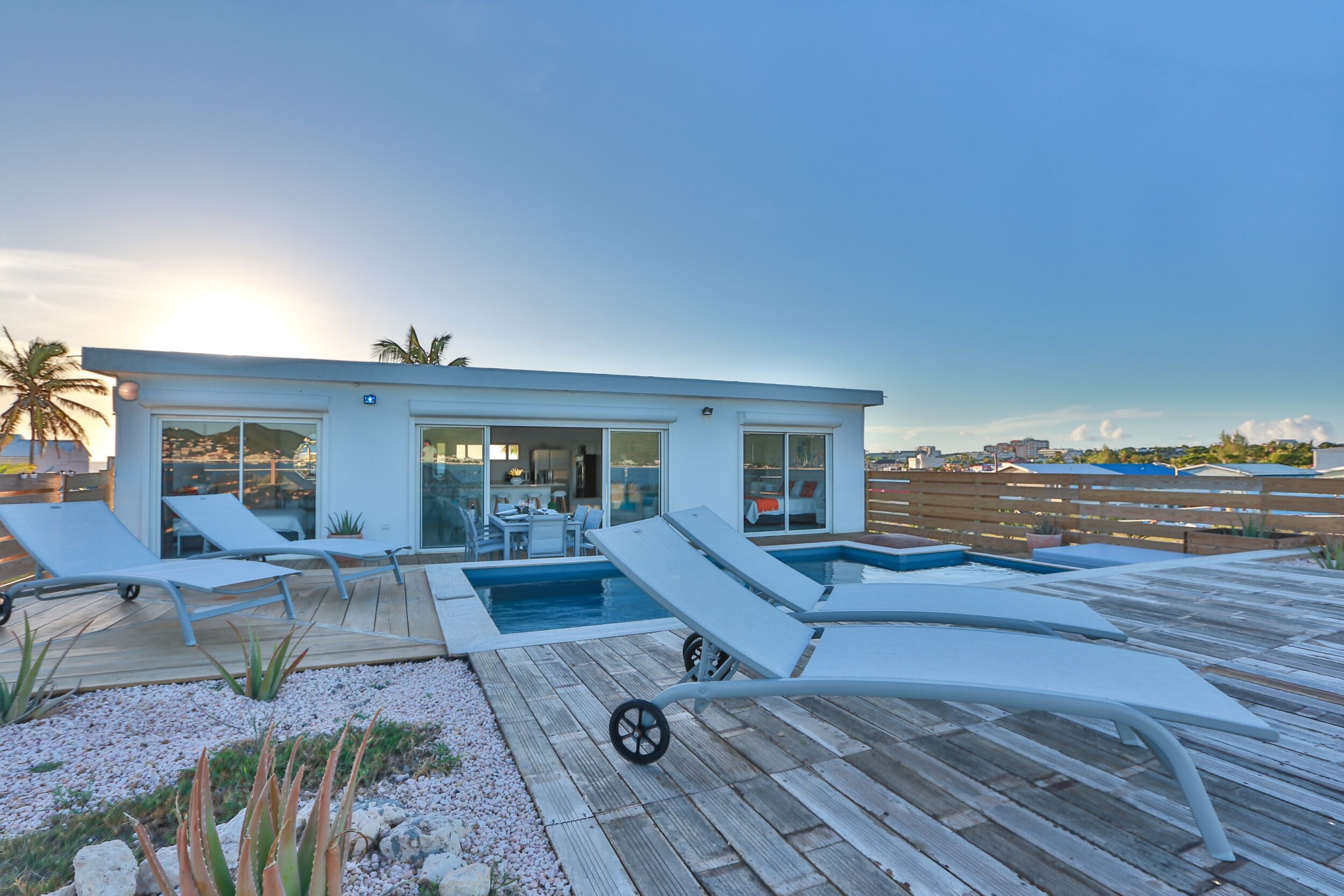 Une maison moderne dotée d’une piscine, de chaises longues et d’une terrasse en bois.