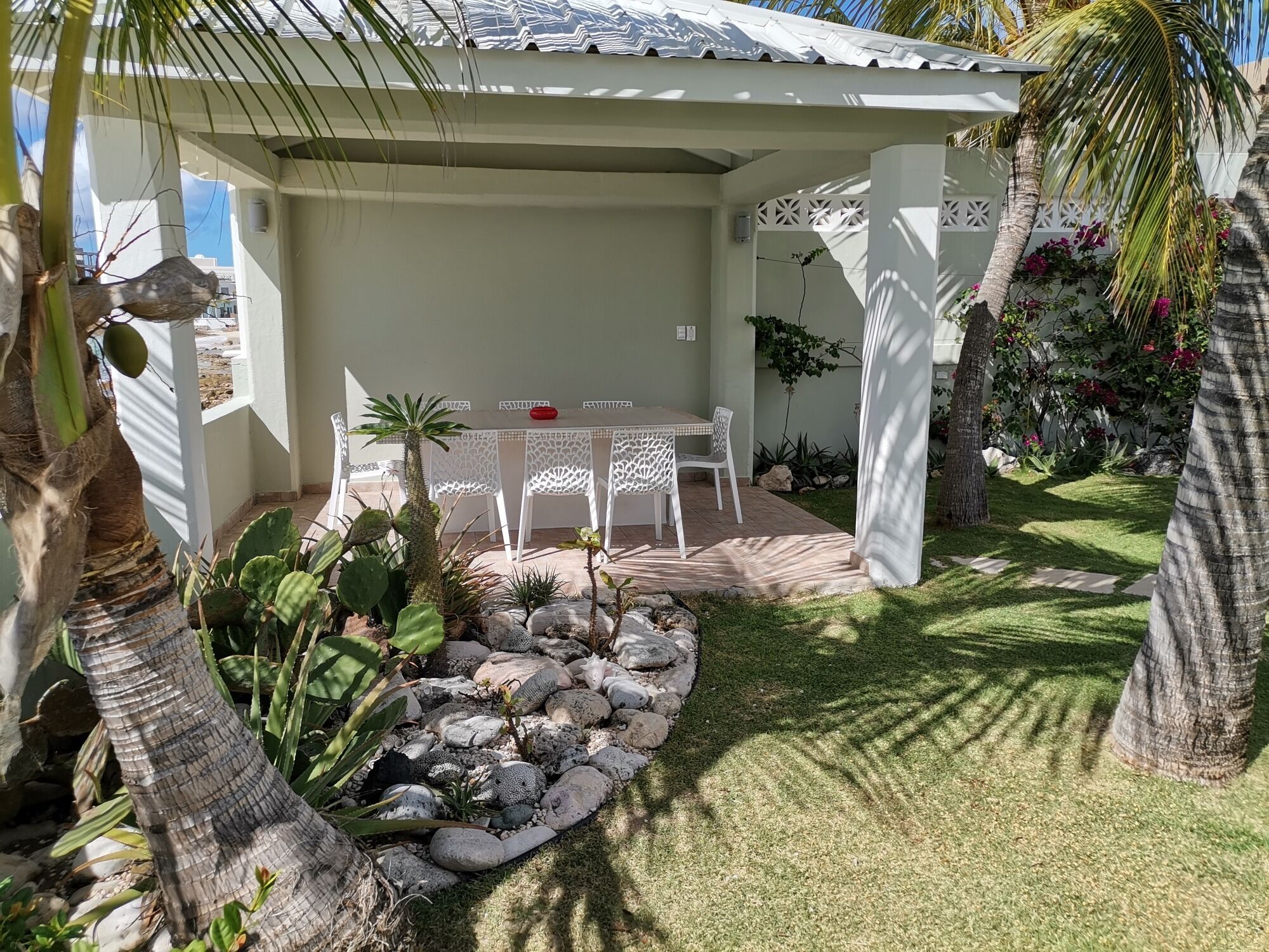 A patio with a table and chairs, surrounded by rocks and plants.