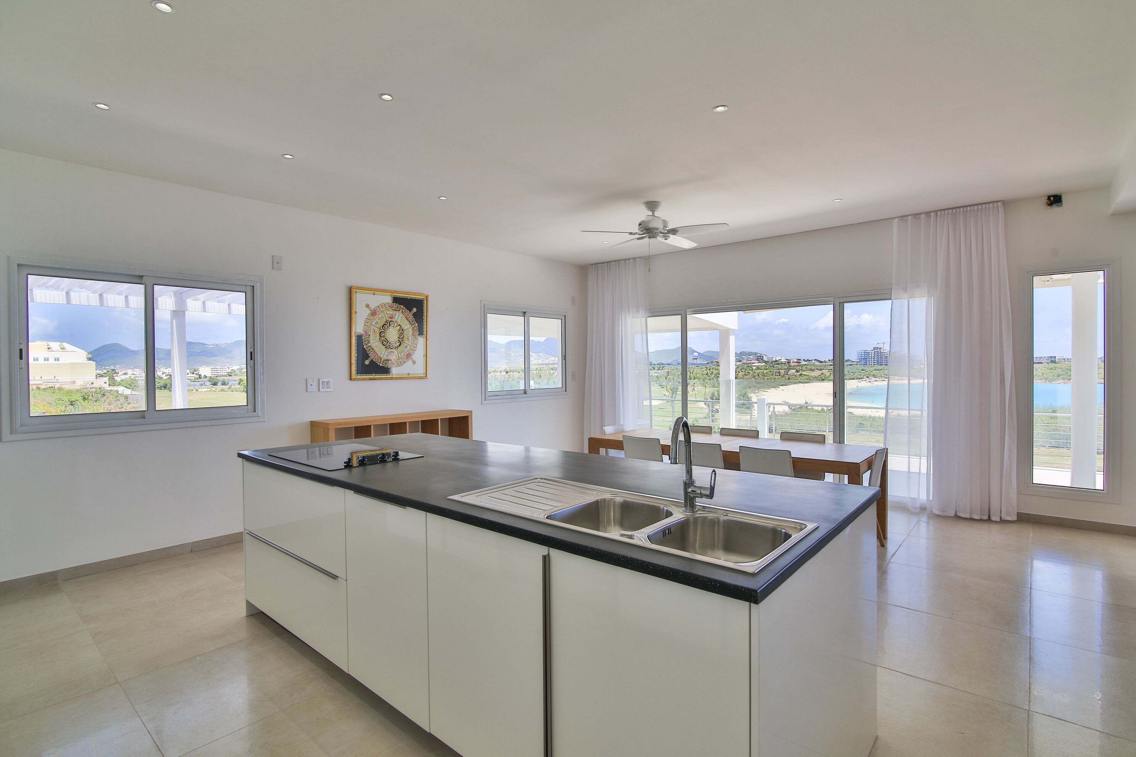 Una cocina moderna con una isla grande, un área de comedor y ventanas amplias que ofrecen vistas al paisaje.