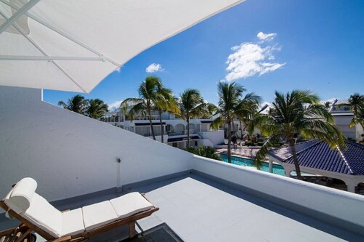 Eine Dachterrasse mit Pool, Palmen und Liegestühlen.
