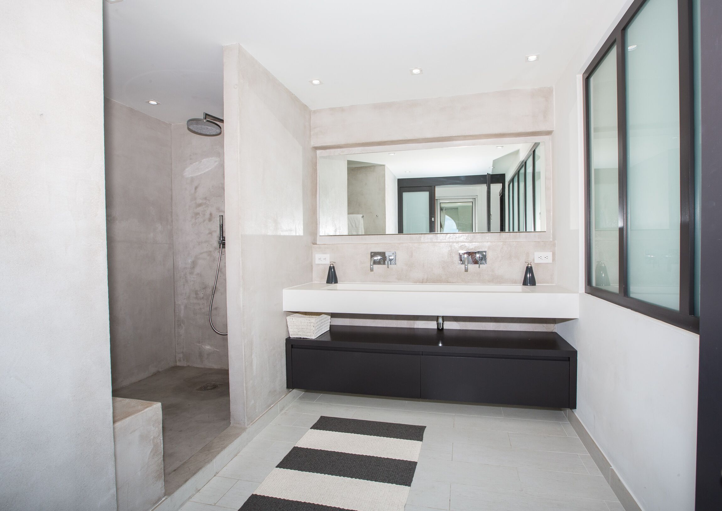 Un baño moderno con cabina de ducha, un espejo grande y un mueble de tocador doble.