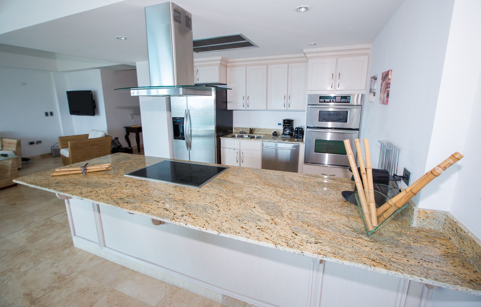 A modern kitchen with a granite countertop, stainless steel appliances, and white cabinetry.