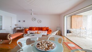 A modern living room with a sofa, chairs, a dining table, and a large window. - Sapphire Fatastic (Lowlands)