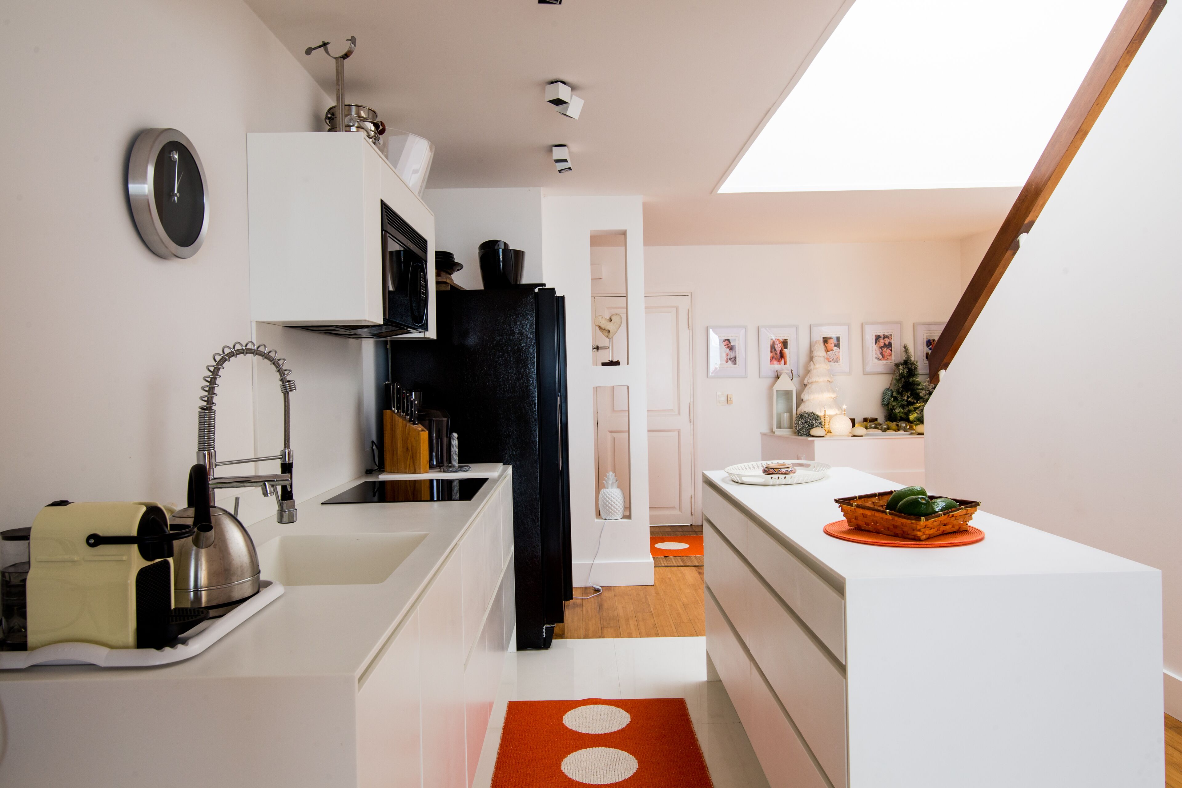 A modern kitchen with white cabinetry, a black refrigerator, and a kettle on the counter.