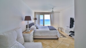 A hotel room with a bed, a desk, a TV, and a view of the sea. - Sapphire Fatastic (Lowlands)