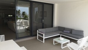 Uma sala de estar moderna com um sofá seccional cinza, mesa de centro branca e cadeiras brancas.