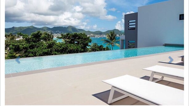 Uma área de piscina moderna com vista desobstruída para montanhas e um corpo d'água ao fundo.