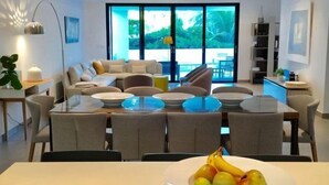 Uma sala de estar moderna com área de jantar, janelas amplas e ventilador de teto.