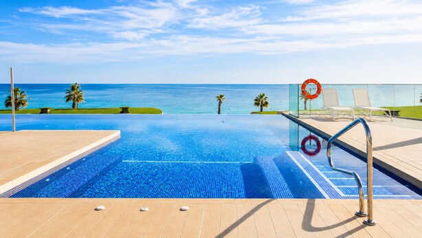 Une piscine d’un bleu éclatant, avec vue sur l’océan, des chaises longues et un anneau de sauvetage.