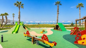 Une aire de jeux avec une balançoire, un toboggan et une structure d’escalade.