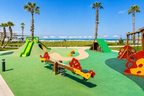 Une aire de jeux avec une balançoire, un toboggan et une structure d’escalade.