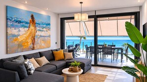 Un salon moderne avec un canapé, une table basse et un tableau représentant une femme au bord de la mer.