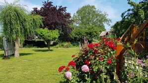 A well-maintained garden with a variety of trees, a wooden structure, and a grassy lawn.