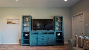 A living room with a teal entertainment center, a flat-screen TV, and a gray sofa.