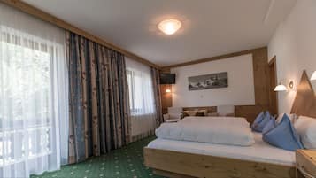 A bedroom with a wooden bed, a flat-screen TV, a mounted artwork, and a wooden nightstand.