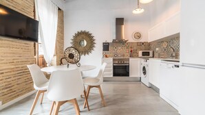 A modern kitchen with white cabinetry, a built-in oven, microwave, and dishwasher. There is a dining area with a round table and white chairs. - MY LOFT 4 YOU RUZAFA STYLE III (Valencia)