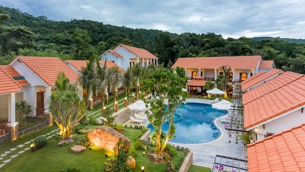 Un complexe hôtelier comprenant plusieurs villas, une piscine centrale et une végétation luxuriante.