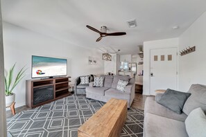 Ein modernes Wohnzimmer mit einem grauen Sofa, einem Holztisch und einem Fernseher auf einem Schrank.