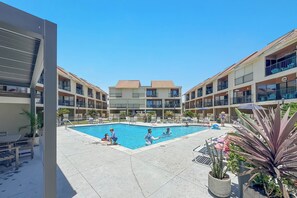 Un'area piscina con diversi livelli di balconi, lettini e piante in vaso.