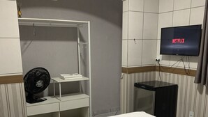 A hotel room with a bed, a TV mounted on the wall, a fan, and a small table. - Pousada EAS GRU Airport (Guarulhos)