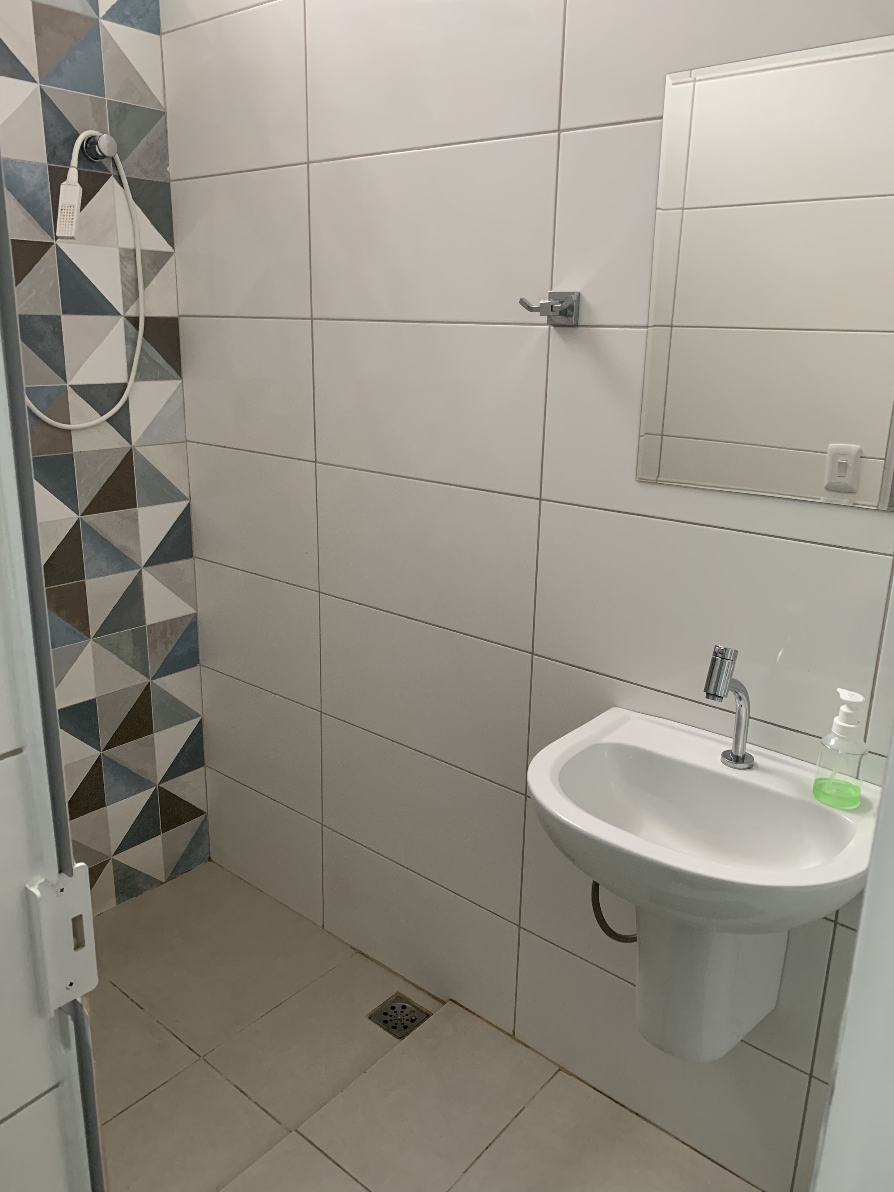 A bathroom with a shower, a sink, and a mirror.