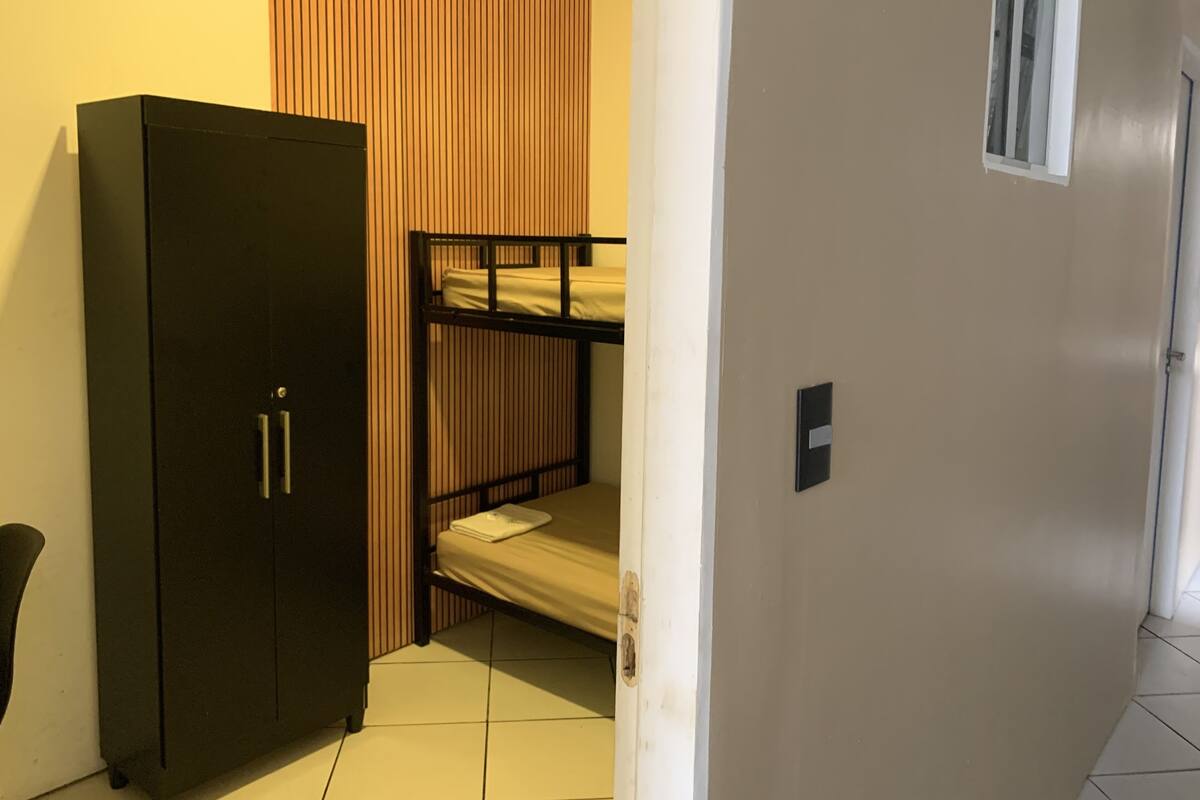 A room with a bunk bed, a wardrobe, and a small window.