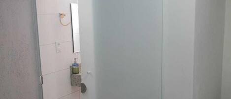 A room with a sliding door leading to a bathroom. The bathroom has a toilet, a sink, and a mirror. There is a small rug on the floor near the door.