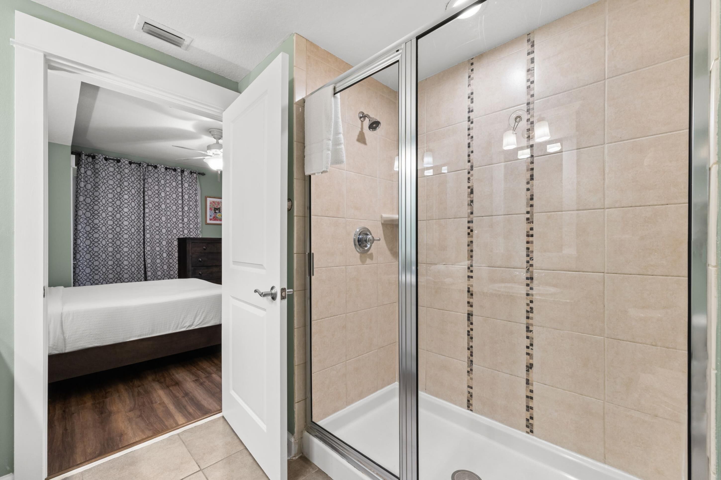 Una stanza con un letto, una doccia con porta in vetro e un bagno con rivestimento piastrellato.