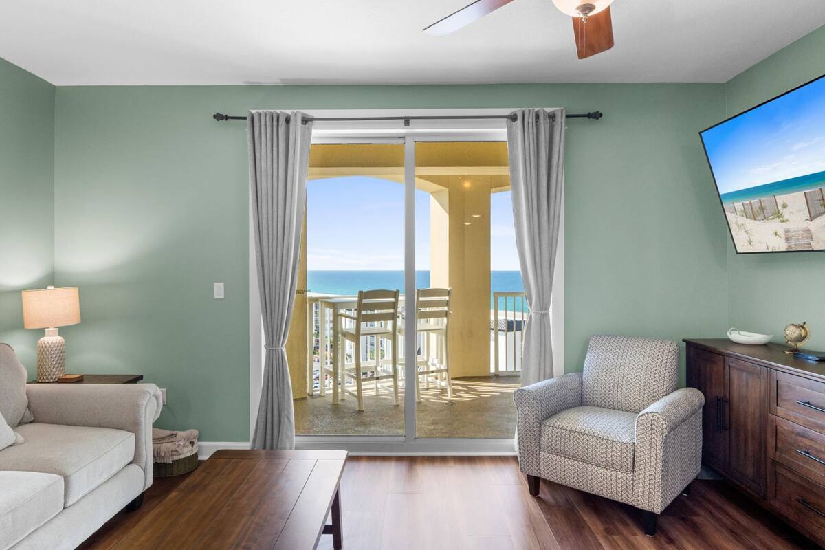 A room with a sliding glass door leading to a balcony with a view of the ocean.