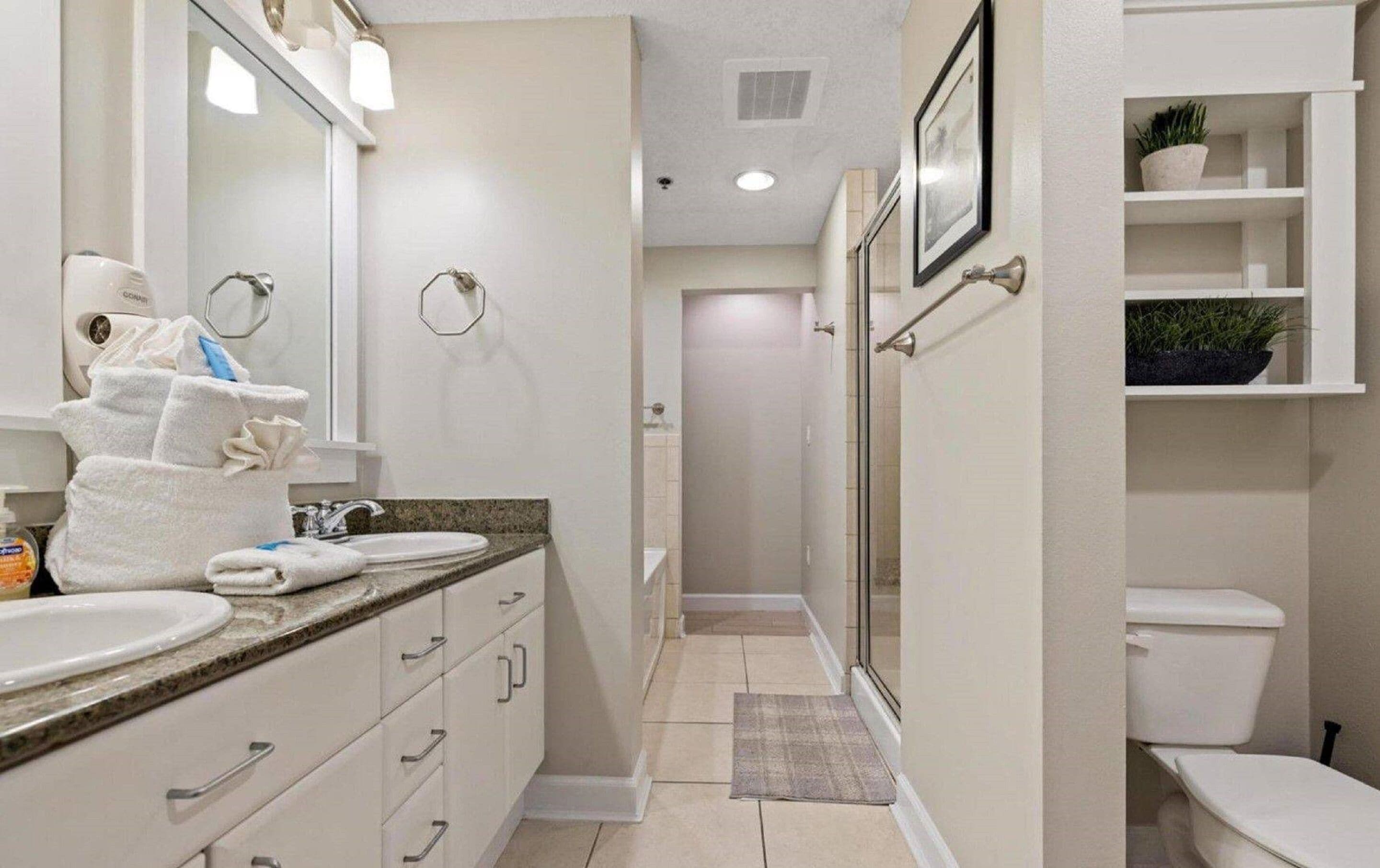 A modern bathroom with a vanity, sink, and toilet. There are towels and toiletries on the counter.