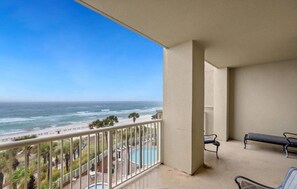 A balcony with a view of the ocean and beach, a pool, and two benches. - Grand Panama Beach Resort - PET Friendly by Panhandle Getaways (Panama City Beach)