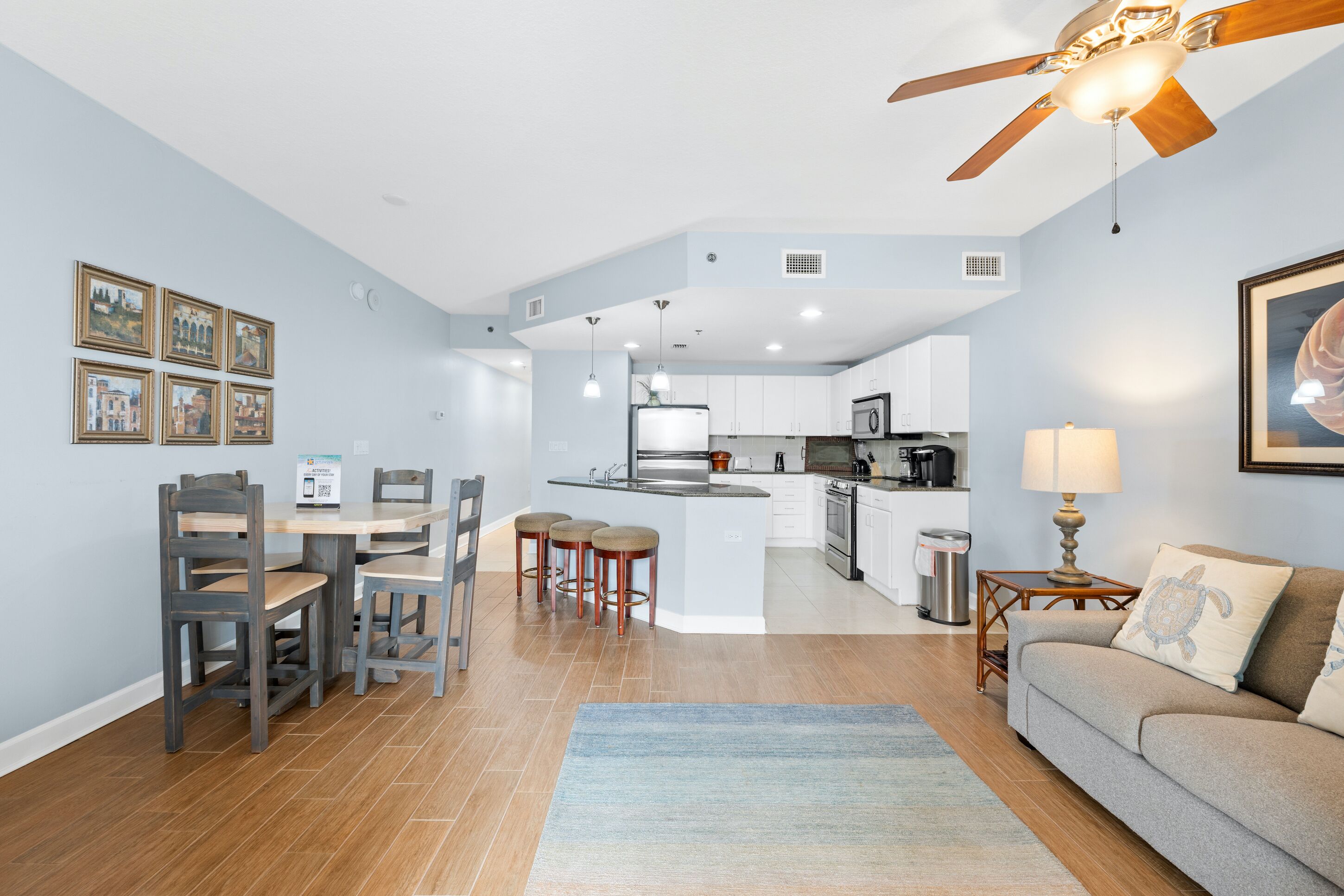 A modern kitchen with white cabinets, a central island, and a dining area with wooden chairs.