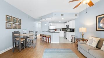 A modern kitchen with white cabinets, a central island, and a dining area with wooden chairs.