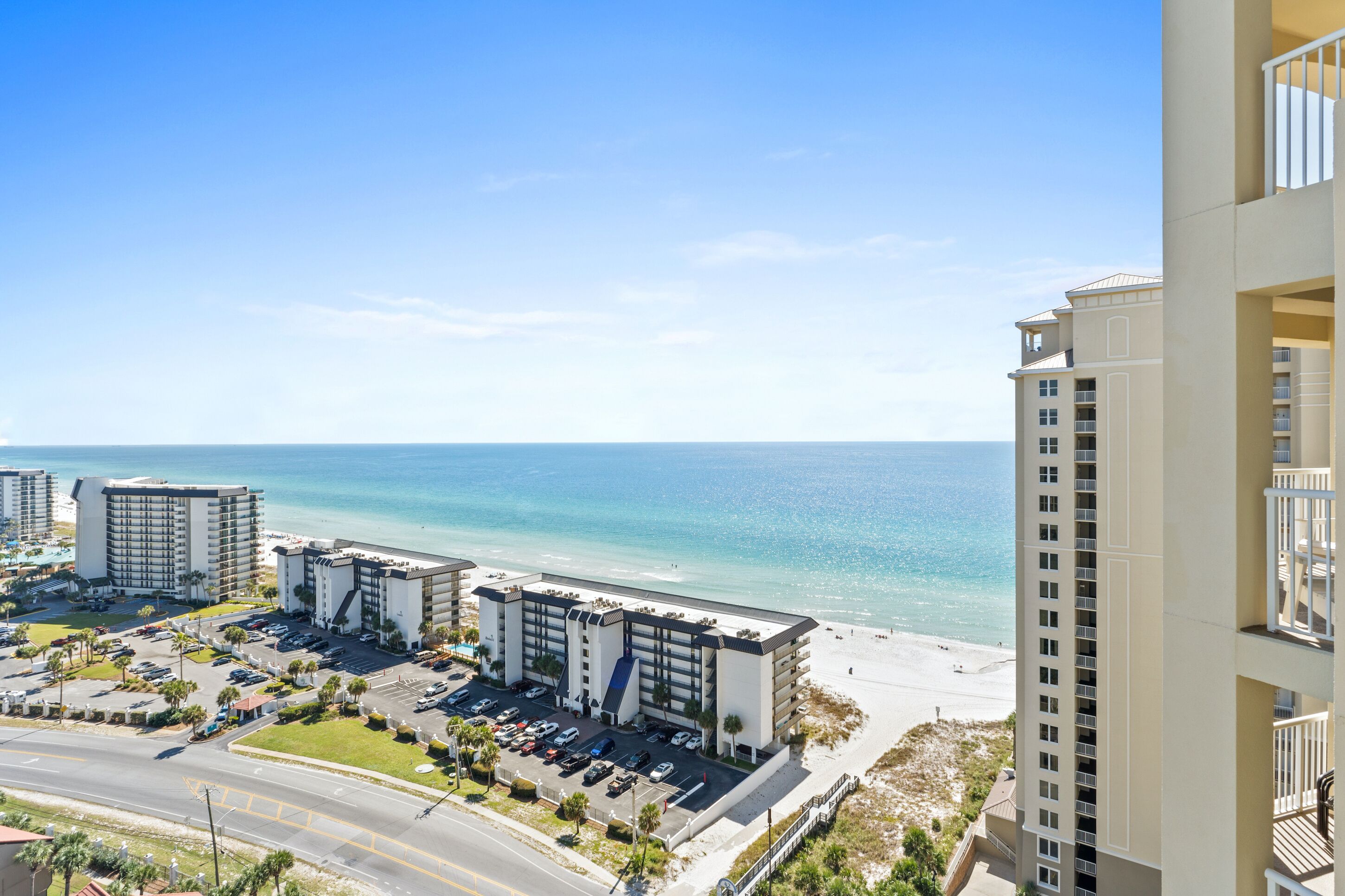Un hotel sulla spiaggia con diversi edifici, un parcheggio e vista mare.