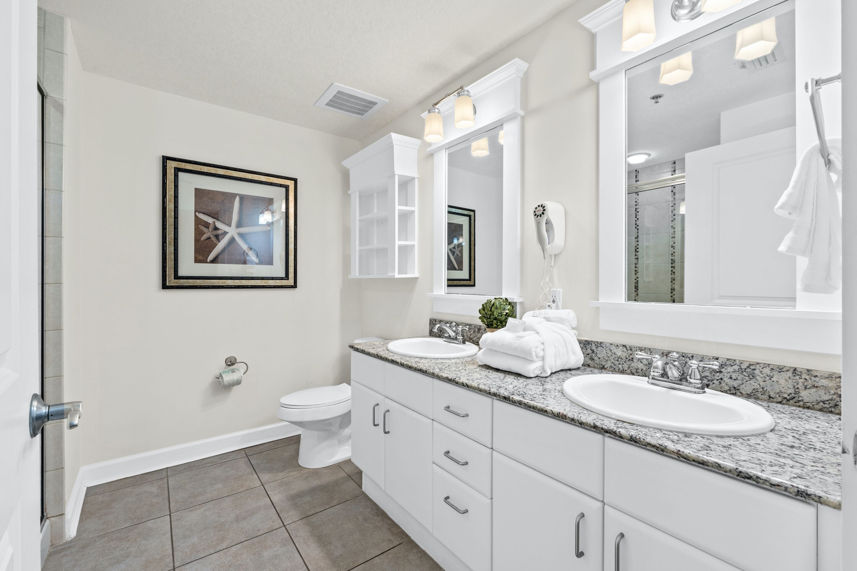 A modern bathroom with two sinks, a large mirror, and a framed picture on the wall.