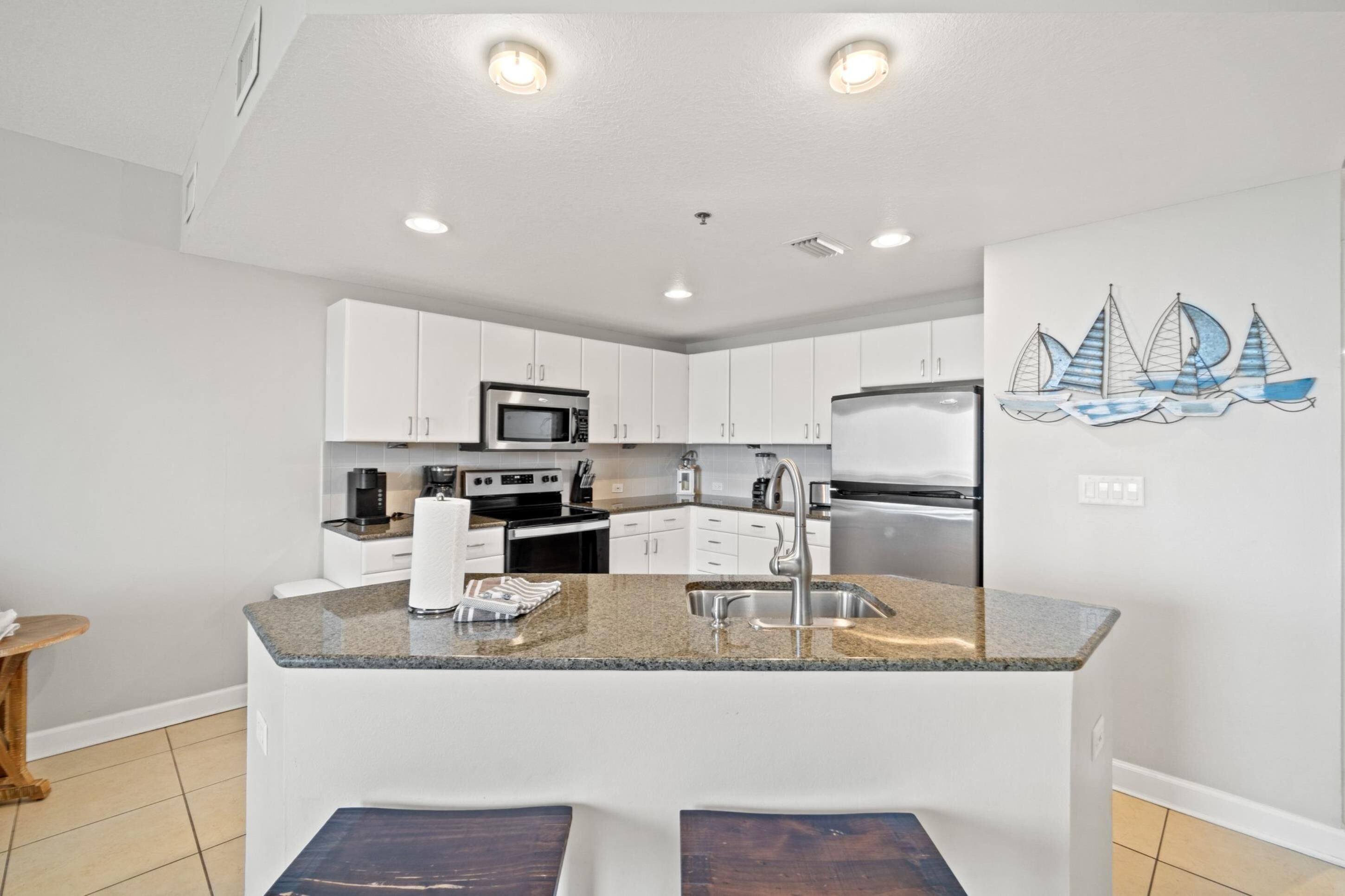 A modern kitchen with white cabinets, stainless steel appliances, and a granite countertop.