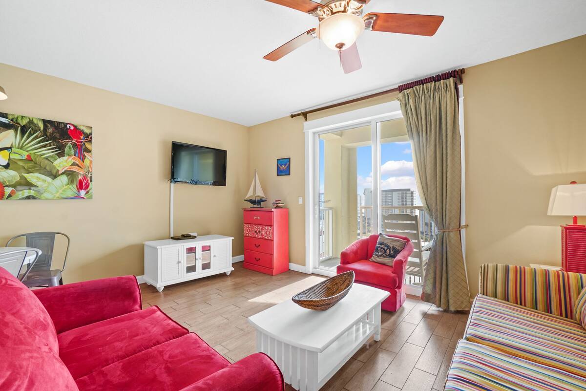 A living room with red furniture, a white cabinet, a television, and a ceiling fan.