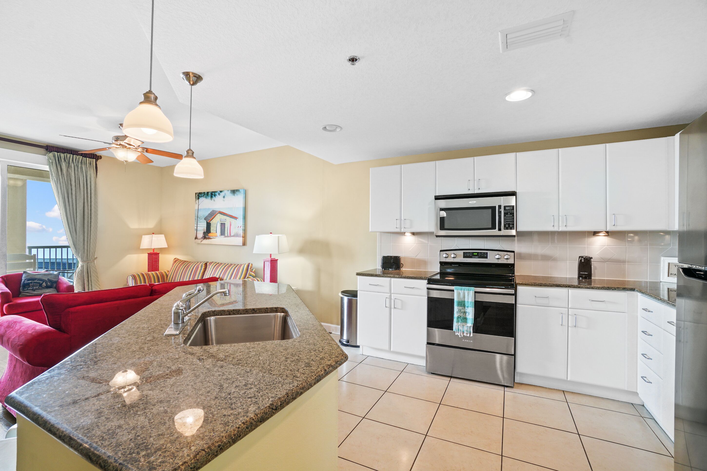 A modern kitchen with granite countertops, stainless steel appliances, and white cabinetry.