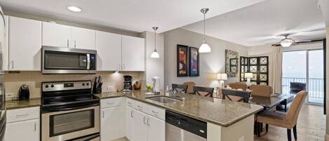 Una cocina moderna con electrodomésticos de acero inoxidable, una isla central y un comedor con vistas.