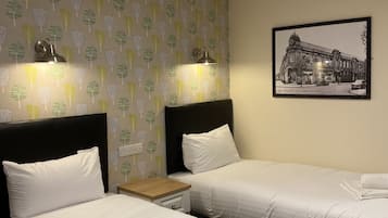 A hotel room with two beds, a nightstand, and a wall-mounted picture.