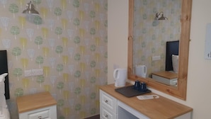A small, tidy room with a wooden desk, a mirror, a kettle, and a patterned wallpaper. - The Bournbrook Inn (Birmingham)