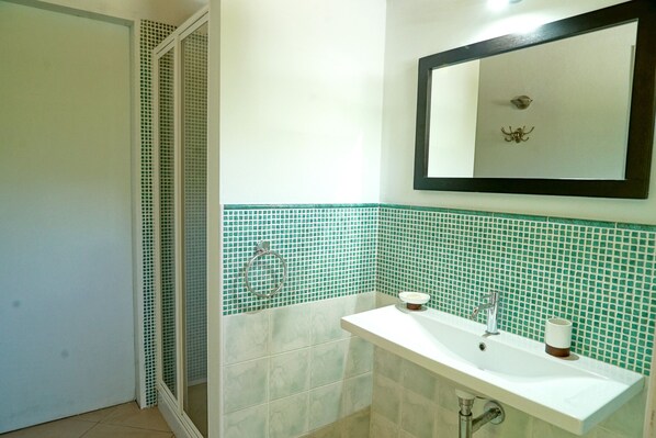 A bathroom with a sink, mirror, and green-tiled walls.