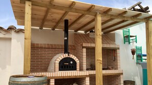 An outdoor brick oven under a wooden pergola.