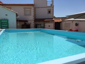Une piscine à l’eau d’un bleu limpide, entourée d’un bâtiment doté d’un toit en tuiles et d’une enseigne indiquant la présence d’un centre de bien-être.