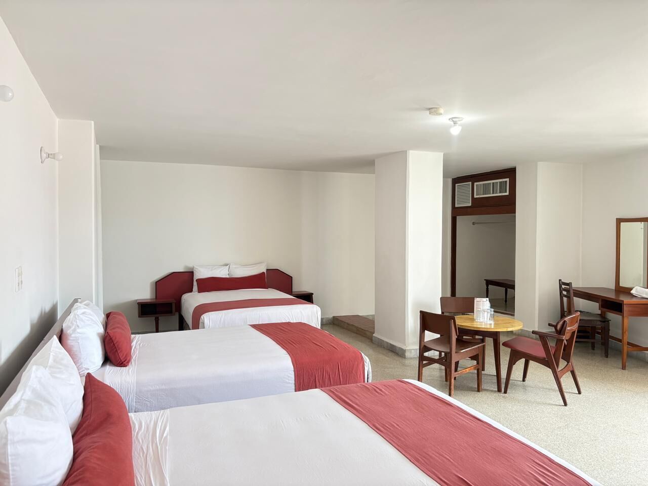 A hotel room with two beds, a desk, and a chair.